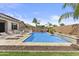 Backyard featuring a sparkling blue swimming pool with travertine tile, surrounded by lush landscaping and lounge chairs at 23097 N 95Th Dr, Peoria, AZ 85383