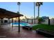 Relaxing backyard with a pristine pool, covered patio, grass, privacy wall and lush tropical landscaping at 3054 W Redfield Rd, Phoenix, AZ 85053