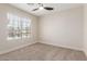 This bedroom features a neutral color palette, carpet, ceiling fan, and a bright window overlooking the neighborhood at 33287 N Windmill Run, San Tan Valley, AZ 85144