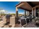 Covered patio area featuring a built-in grill, outdoor seating, and view of the desert landscape at 40619 N Candlewyck Ln, Phoenix, AZ 85086