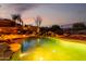 Backyard pool featuring stone accents, built-in spa, desert landscaping, and outdoor fireplace at dusk at 40619 N Candlewyck Ln, Phoenix, AZ 85086