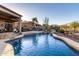 Stunning backyard pool with rock features, desert landscaping, and outdoor kitchen provides a luxurious retreat at 40619 N Candlewyck Ln, Phoenix, AZ 85086