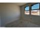 A bright, unfinished bedroom with two windows offering street views and natural light at 46869 W Old Timer Rd, Maricopa, AZ 85139