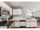Well-lit kitchen with modern appliances, white cabinets, tile backsplash, and view to the living room at 4741 N 85Th Ave, Phoenix, AZ 85037
