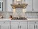 Close up of modern stove top, range hood, and marble backsplash in kitchen at 4935 W Lariat Ln, Phoenix, AZ 85083