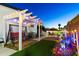 Charming backyard featuring a pergola with string lights, a swing, and desert landscaping at 5534 E Player Pl, Mesa, AZ 85215