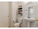 Cozy powder room featuring pedestal sink and shelves for decor at 6276 N 75Th Ln, Glendale, AZ 85303