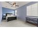 Well-lit bedroom features a large bed, fan, gray carpet, two windows and a dark wood shelf at 7440 E Osage Ave, Mesa, AZ 85212