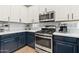 Close-up of a modern kitchen featuring stainless steel appliances, contrasting cabinetry, and quartz countertops at 7440 E Osage Ave, Mesa, AZ 85212