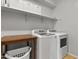 Neat laundry room featuring white washer and dryer, wooden table, storage shelves and a laundry basket at 7440 E Osage Ave, Mesa, AZ 85212