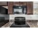 A kitchen showing a stove top and microwave with wood cabinets above against a speckled counter at 7732 W Bonitos Dr, Phoenix, AZ 85035