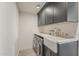 Well-appointed laundry room features gray cabinets, quartz countertops, and a farmhouse sink at 8320 E Monte Vista Rd, Scottsdale, AZ 85257