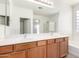 Bright bathroom featuring a double sink vanity, a large mirror, and a shower with glass block at 8541 W Malapai Dr, Peoria, AZ 85345