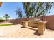 Spacious backyard featuring a tiled patio, outdoor grill, privacy wall, and mature landscaping at 8541 W Malapai Dr, Peoria, AZ 85345