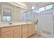 Bright bathroom with double vanity, large mirror, and glass-enclosed shower at 11038 W Oraibi Dr, Peoria, AZ 85373