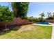 A backyard featuring a pool, grass area, brick fence, and various plants and trees at 1247 E Bautista Rd, Gilbert, AZ 85297