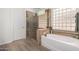 Well-lit bathroom with a soaking tub, glass enclosed shower, and glass block window at 1247 E Bautista Rd, Gilbert, AZ 85297
