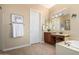 Bright bathroom features a vanity with makeup area, a large mirror and a tub at 13219 W Santa Ynez Dr, Sun City West, AZ 85375