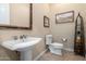 Elegant bathroom featuring a pedestal sink, toilet, and decorative artwork at 13219 W Santa Ynez Dr, Sun City West, AZ 85375