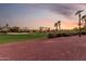 Scenic view of the lush green golf course dotted with palm trees and framed by a vibrant sunset at 13219 W Santa Ynez Dr, Sun City West, AZ 85375