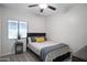 A cozy bedroom has carpeted floors, a ceiling fan, a window, and a bed with a gray duvet and decorative pillows at 1364 W Spine Tree Ave, Queen Creek, AZ 85140