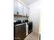 A laundry room featuring overhead cabinets and stainless steel washer and dryer units at 1364 W Spine Tree Ave, Queen Creek, AZ 85140