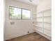 Bright laundry room with wood floor, window and white shelving at 13862 W Fargo Dr, Surprise, AZ 85374