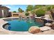 Backyard pool with stone waterfall feature surrounded by mature landscaping at 14572 W Medlock Dr, Litchfield Park, AZ 85340