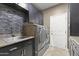 This laundry room features sleek washer/dryer units, stylish backsplash, and upper and lower cabinets at 15928 W Zinnia Ct, Surprise, AZ 85374
