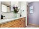 Bathroom with double sinks, wood cabinets, decorative mirror, and a vase of flowers at 16210 W Durango St, Goodyear, AZ 85338