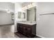 A bathroom with double sinks, dark wood cabinets, and a large mirror at 17345 W Spur Dr, Surprise, AZ 85387