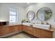Bright bathroom featuring double sinks with modern faucets and a wood vanity cabinet under a window at 1750 E Mallory St, Mesa, AZ 85203