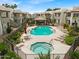 Community pool area showcasing a pool, hot tub, lounge chairs, tables, umbrellas, and lovely landscaping at 1825 W Ray Rd # 1119, Chandler, AZ 85224