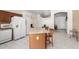 Kitchen featuring a functional island, white appliances, tile floors, arched doorway and neutral color scheme at 1950 E Kings Ave, Phoenix, AZ 85022