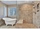 Bright bathroom features free standing tub and walk-in shower with stone tile at 19506 N 73Rd Ave, Glendale, AZ 85308