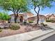 Beautiful desert home with mature trees, decorative rock, and a 