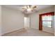 Carpeted bedroom with ceiling fan, window with decorative curtains, and open doorway at 21320 N 56Th St # 1158, Phoenix, AZ 85054
