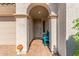 Welcoming front porch with arched entrance, paver flooring, and a blue accent bench, creating a cozy entry space at 25601 N 140Th Ln, Surprise, AZ 85387