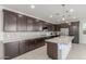 Well-appointed kitchen with dark cabinets, stainless steel appliances, a white countertop island, and mosaic tile backsplash at 25601 N 140Th Ln, Surprise, AZ 85387