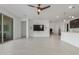 Spacious living room featuring white tile flooring, a modern ceiling fan, and a wall-mounted television for entertainment at 25601 N 140Th Ln, Surprise, AZ 85387