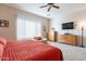Bright bedroom with a large window, wood dresser, TV, and a cozy seating area with an orange comforter at 2567 E San Isido Trl, Casa Grande, AZ 85194