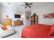 Bedroom featuring a ceiling fan, TV, dresser, and a cozy seating area with an orange comforter at 2567 E San Isido Trl, Casa Grande, AZ 85194
