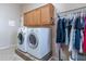 Bright laundry room featuring a washer, dryer, and hanging rack underneath cabinets at 2567 E San Isido Trl, Casa Grande, AZ 85194