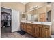 Bright bathroom featuring dual sinks, a large mirror, wood cabinets, and tile flooring at 26264 N 74Th Ln, Peoria, AZ 85383