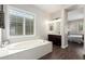 Bright bathroom with large tub, dark wood vanity, and view of the main bedroom at 27562 N 99Th Dr, Peoria, AZ 85383
