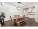 Bright dining room featuring wood-look floors, wooden table, modern light fixture and white shiplap walls at 27562 N 99Th Dr, Peoria, AZ 85383