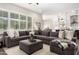 Spacious living room featuring wood-look tile flooring and oversized gray sectional couch open to the kitchen at 27562 N 99Th Dr, Peoria, AZ 85383