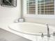 A close up of the large soaking tub with a large window and plantation shutters at 27562 N 99Th Dr, Peoria, AZ 85383