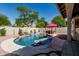 Backyard pool with rock waterfall, mature landscaping, and red umbrellas for shade at 29816 N 51St Pl, Cave Creek, AZ 85331