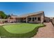 Backyard oasis featuring a putting green, pool with rock features, and covered patio at 29816 N 51St Pl, Cave Creek, AZ 85331